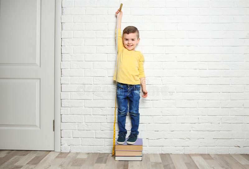little boy measuring his height near wall brick 115308635 1 1 How your height increases every morning ? हर सुबह आपका कद कैसे बढ़ जाता है ?