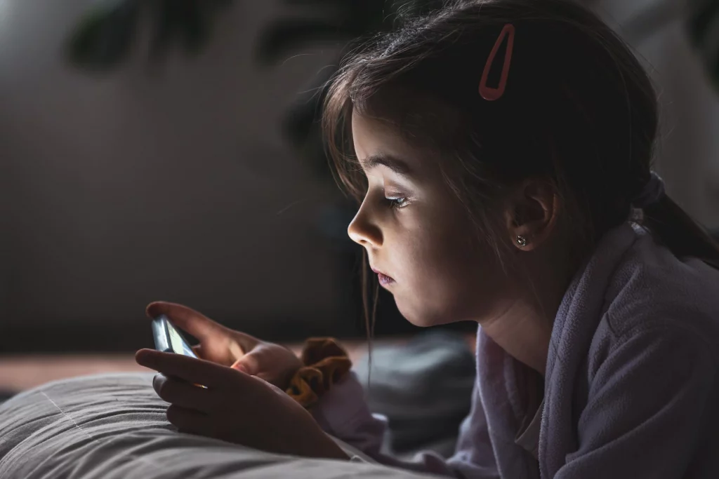 little girl uses smartphone lying pillow home 169016 17139 How Is Your Smartphone Affecting Your Sleep: हम केवल अपने फ़ोन चार्ज करने के लिए सोते हैं